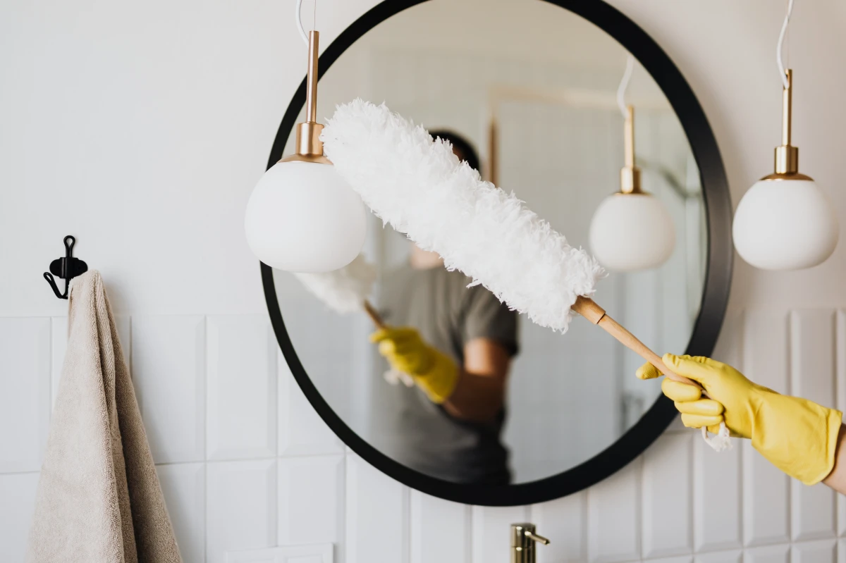 person dusting their mirror