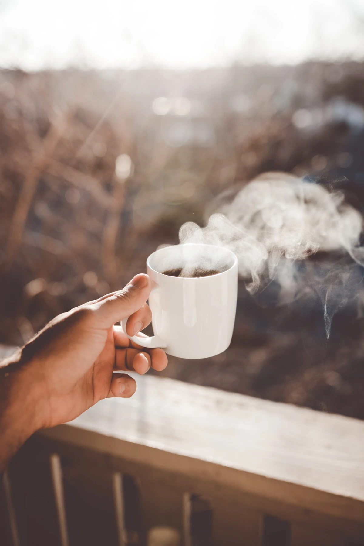 person holding steaming cup of coffee