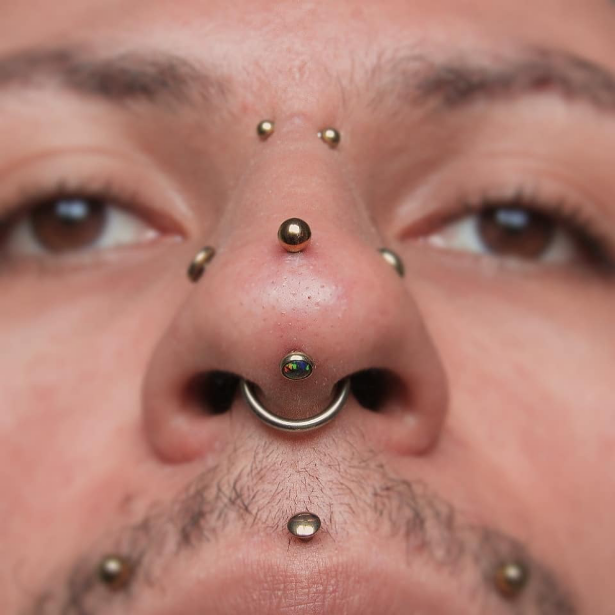 17 man with multiple face nose and mouth piercings
