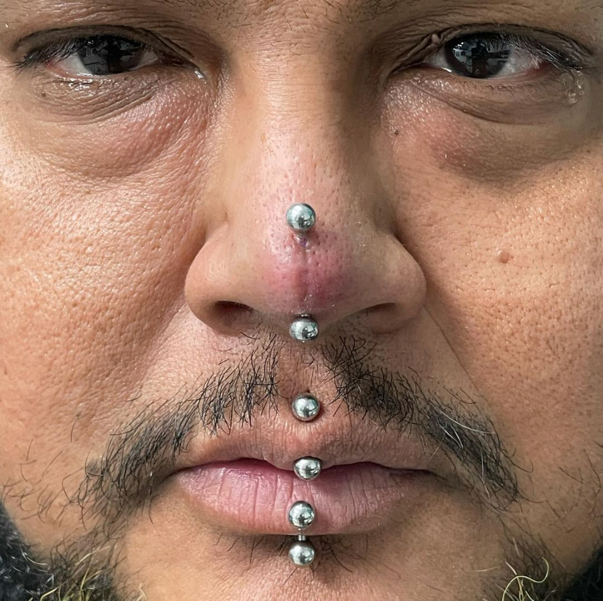 7 man with multiple piercings on nose and mouth
