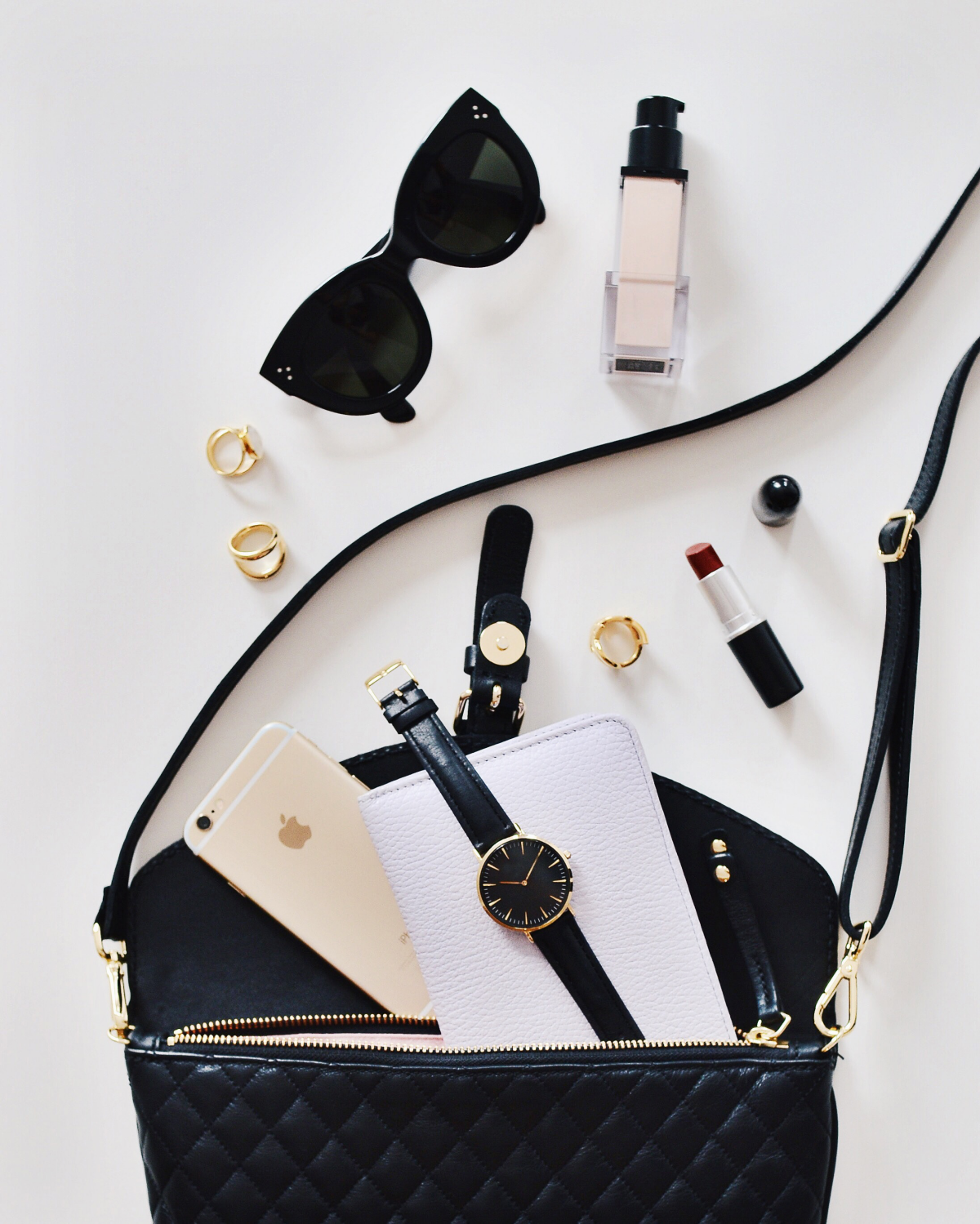 beauty and fashion black bag spilling out makeup and essentials