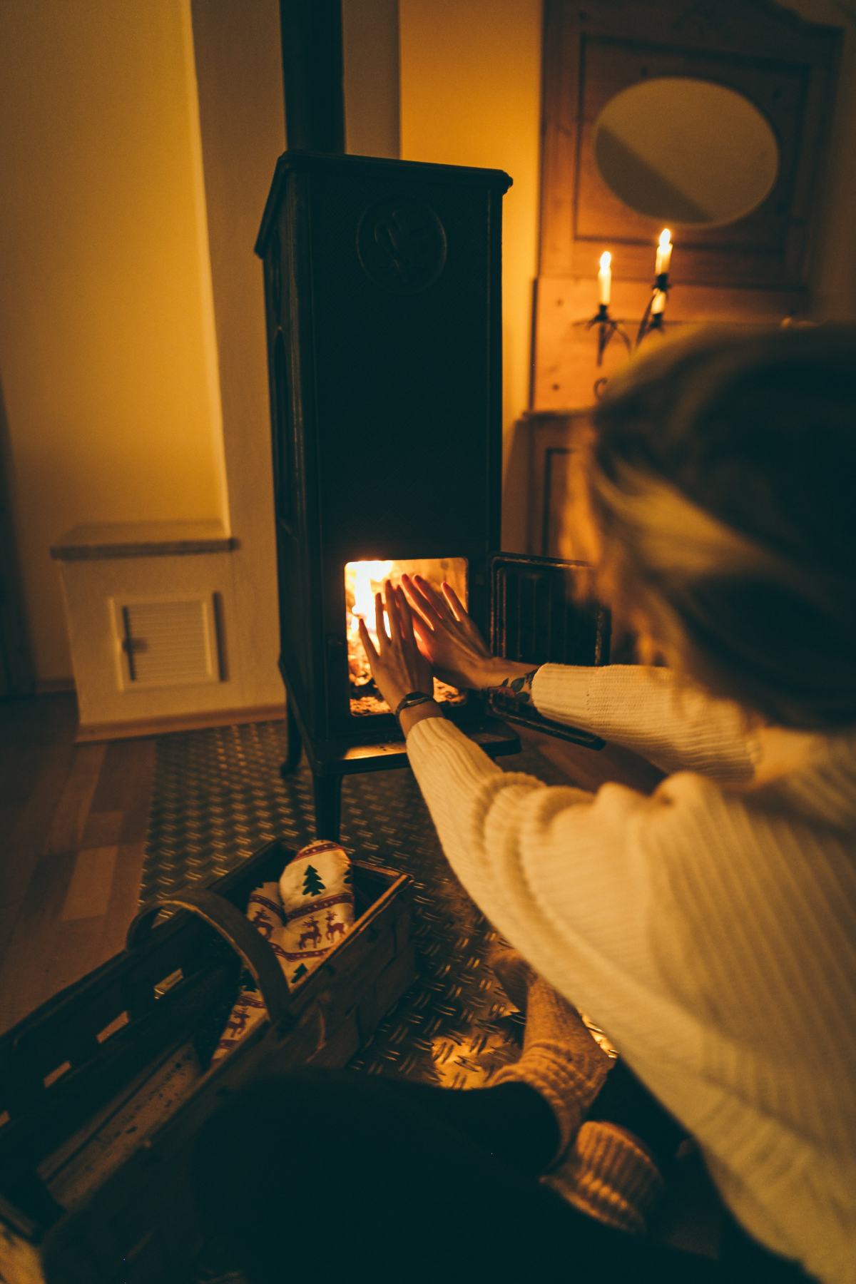 common heating mistakes woman getting warm on fireplace