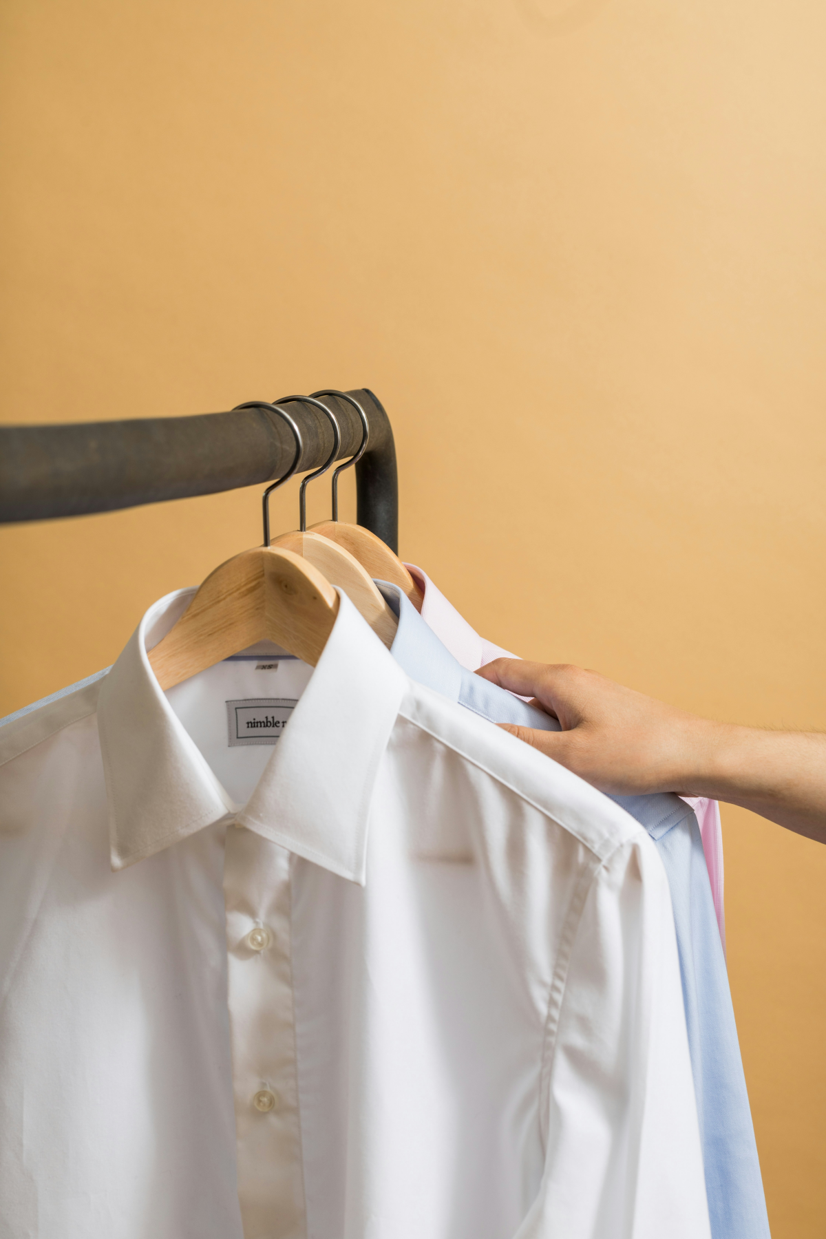 person picking out a dress shirt from hanger