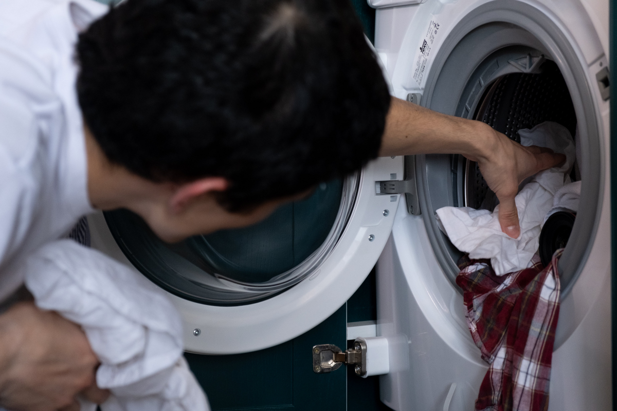 person putting clothes in machine