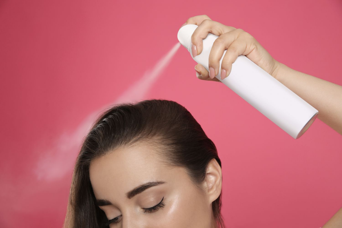 spraying dry shampoo on hair