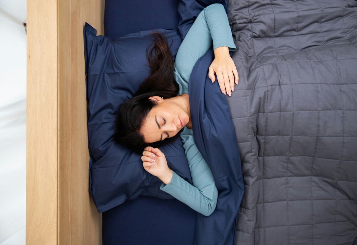woman sleeping under blue weighted blanket