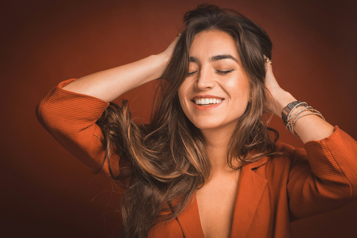 woman smiling while touching her hair