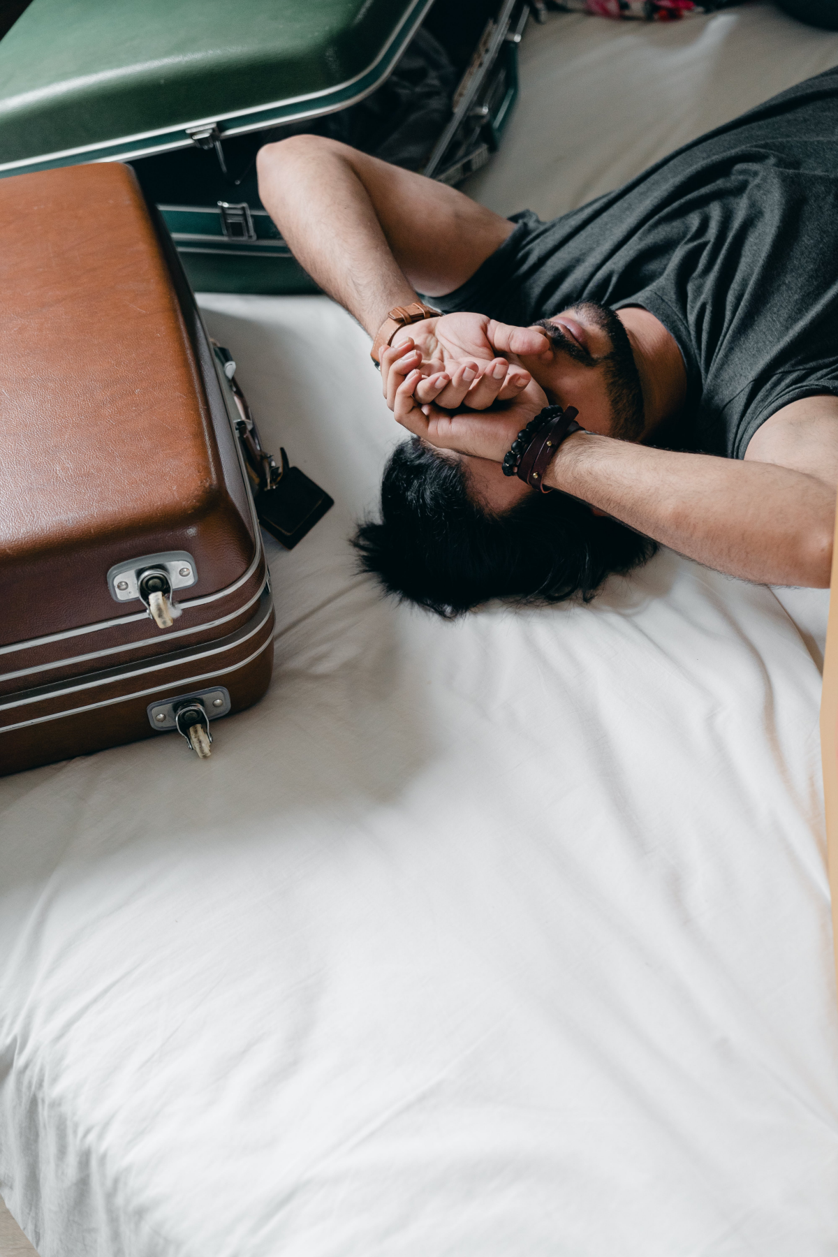 man laying next to suitcases