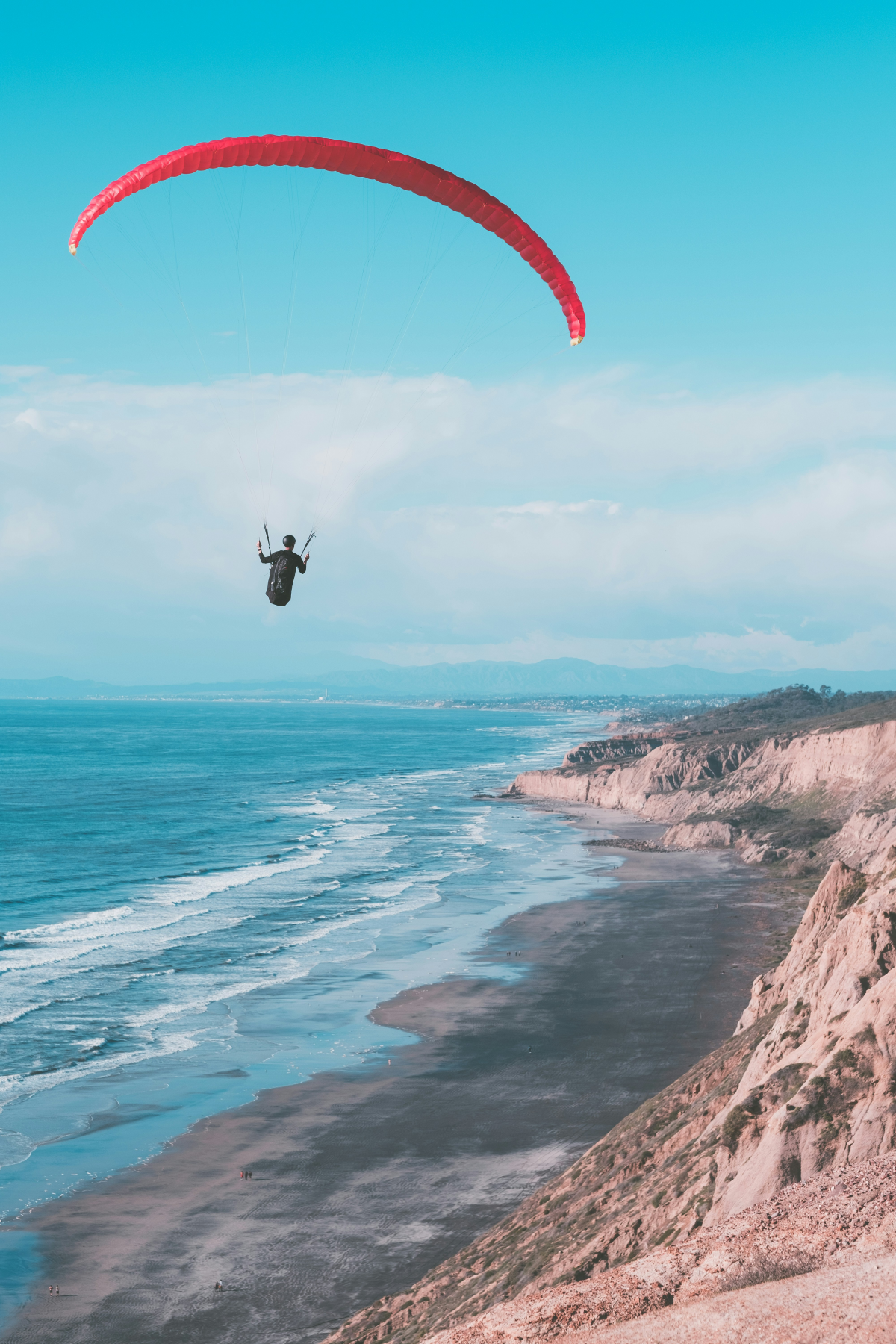person paragliding above beach