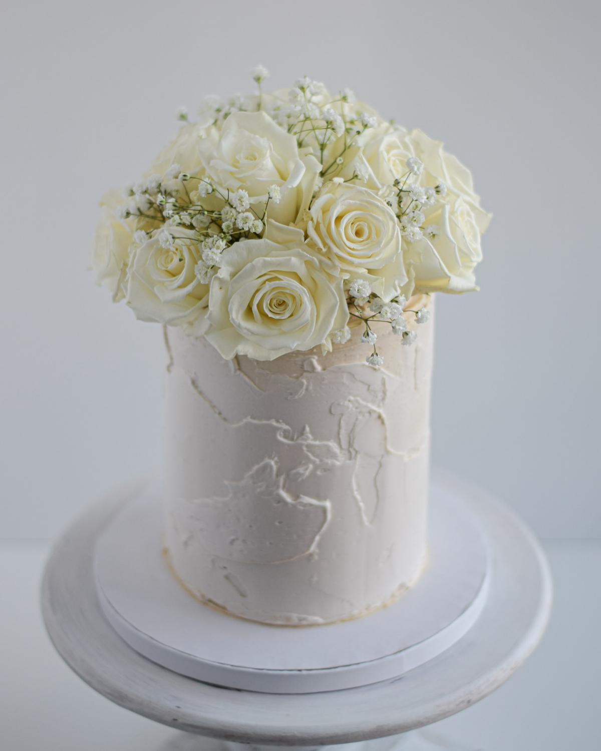 white roses and babys breath on white cake