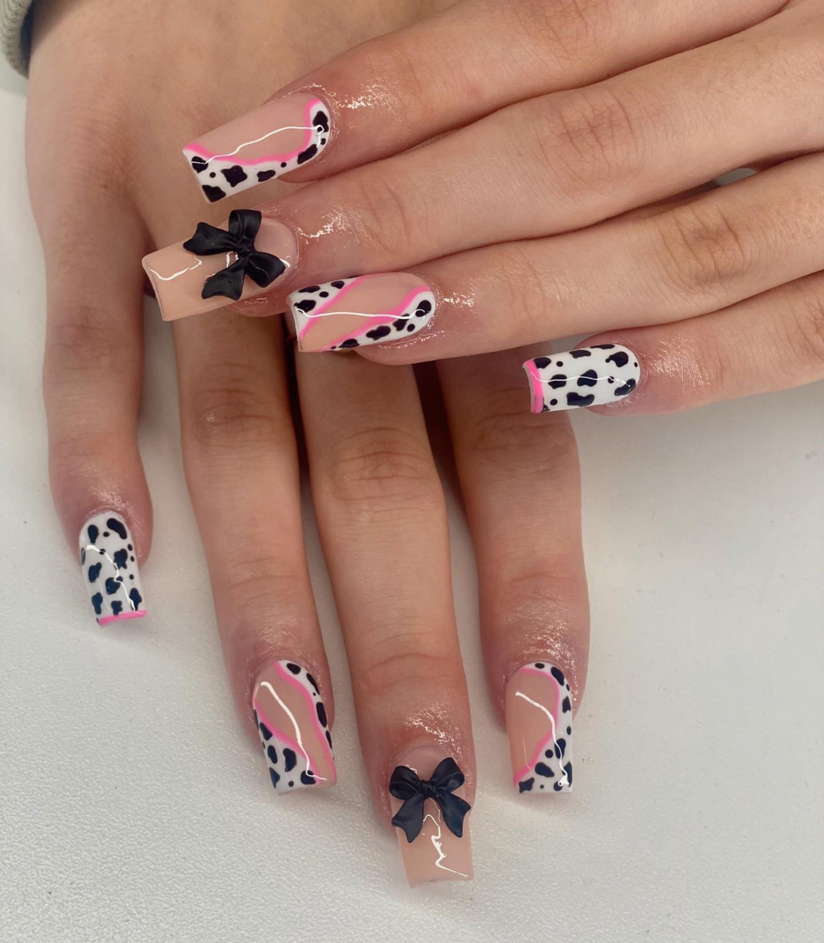 coquette cow print manicure with pink accents and bows